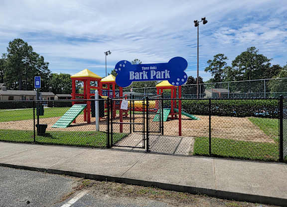 a park with a playground and a blue sign that reads bark park